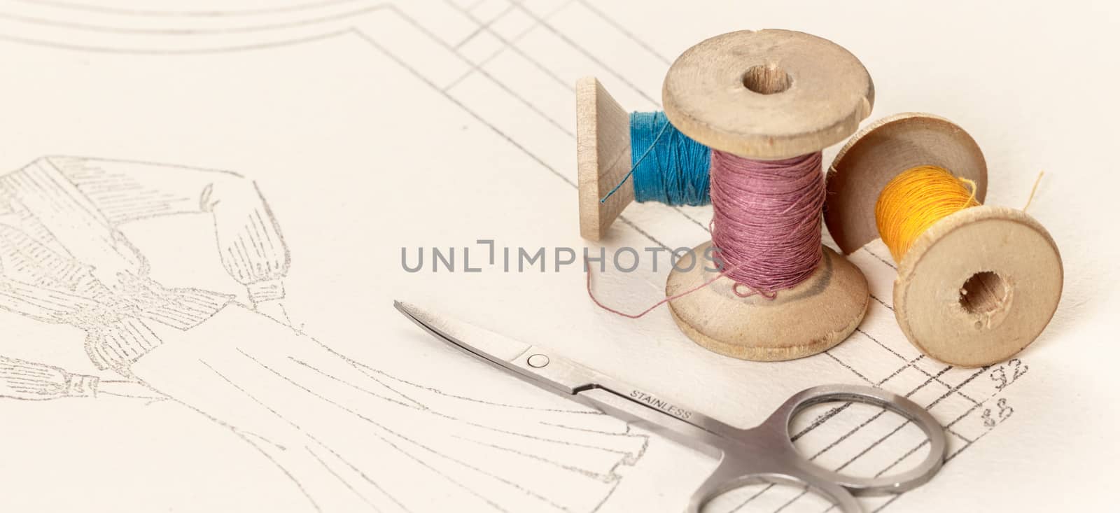 coils of colored threads and scissors on a background of paper pattern