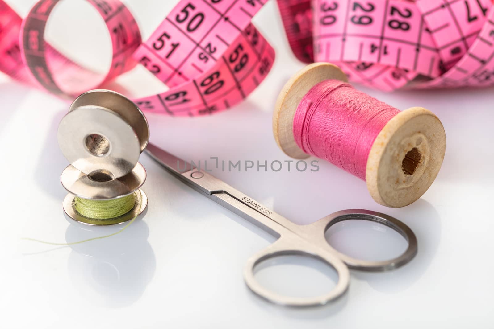 spool of pink thread and meter on white background