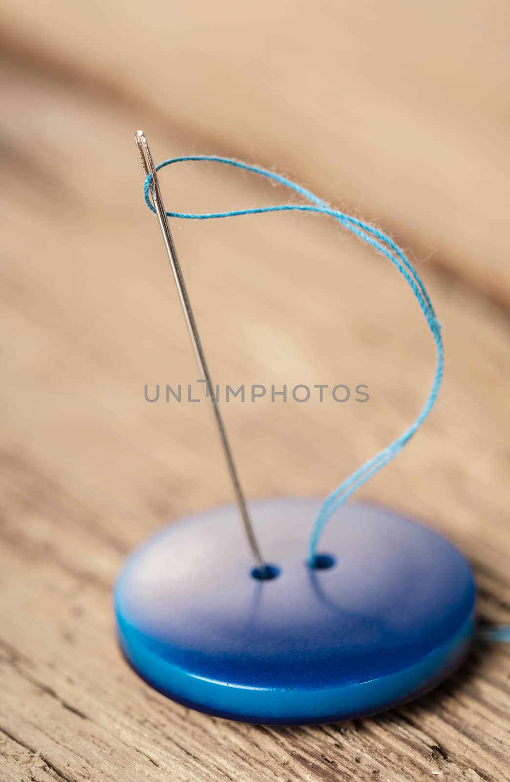 blue button with needle close-up on a wooden background