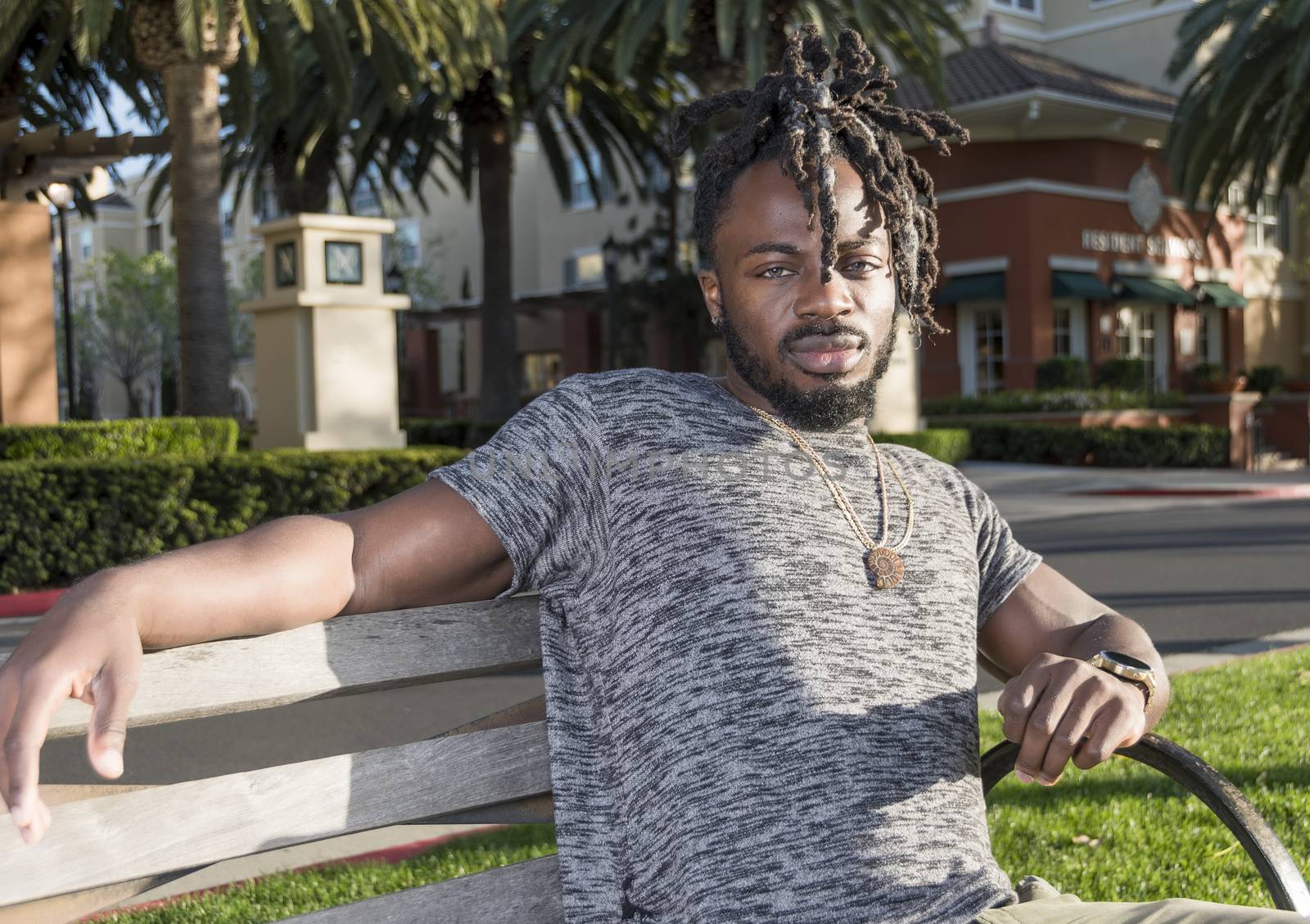 Handsome young African American man sitting on the bench in the park.