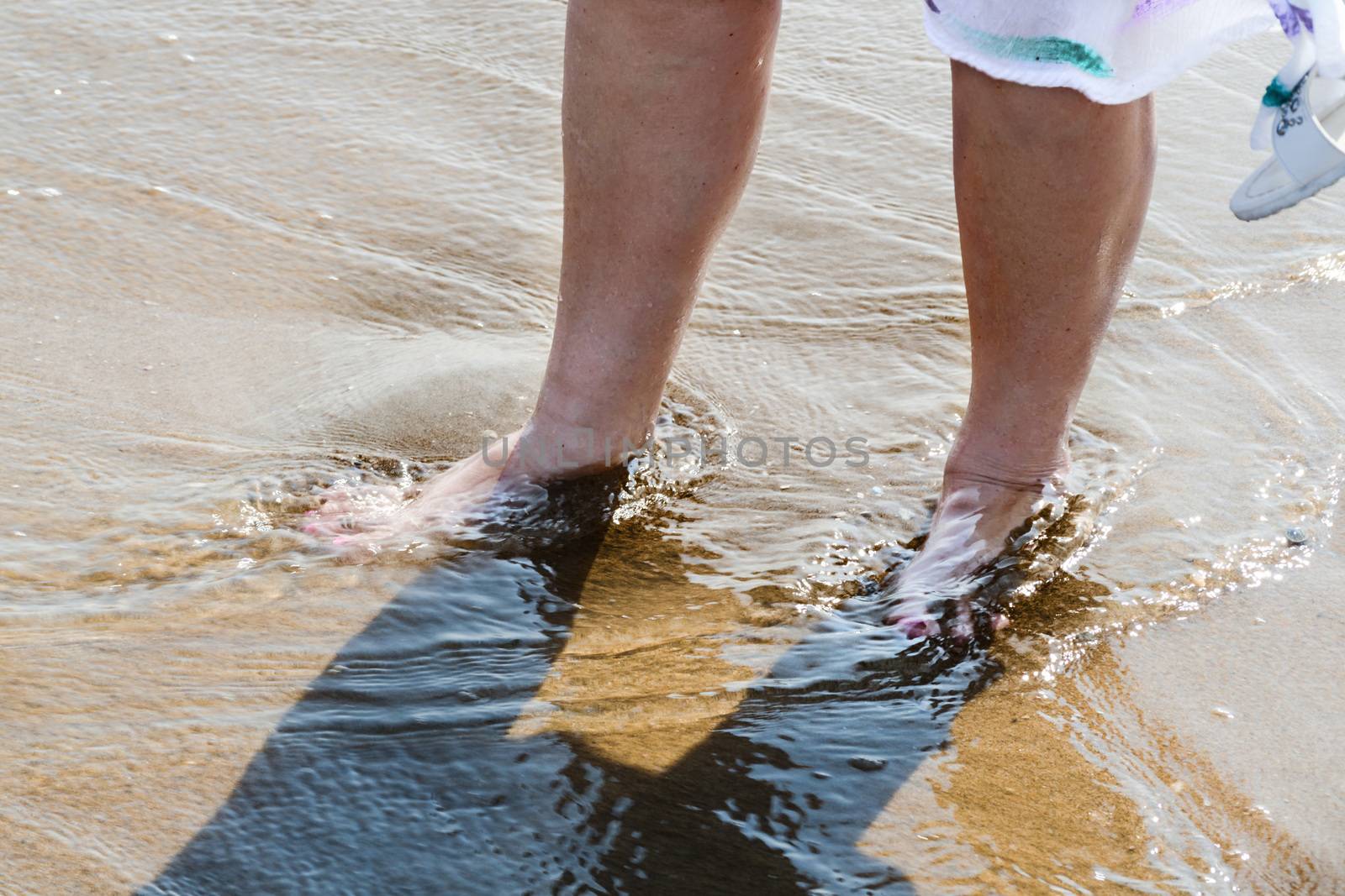 Women legs in the sea at the beach with water splashes and drops