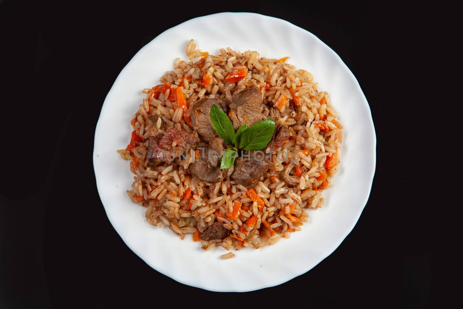 Plate with an asian food pilaw on a black studio background