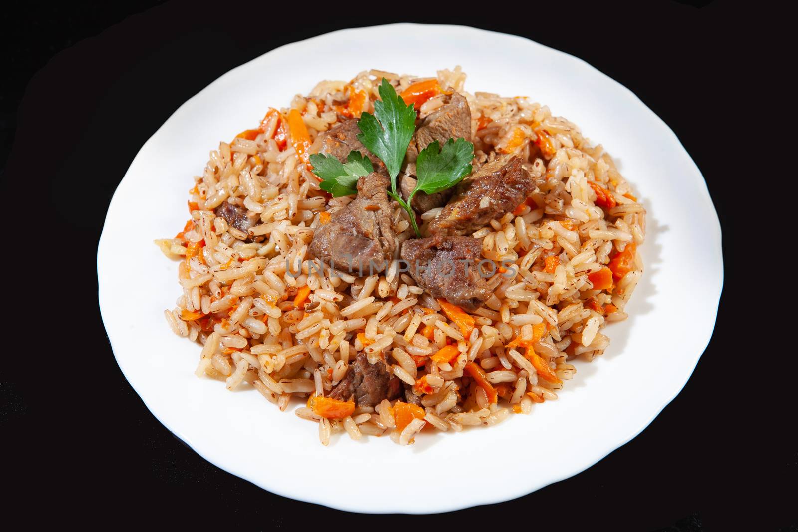 Plate with an asian food pilaw on a black studio background