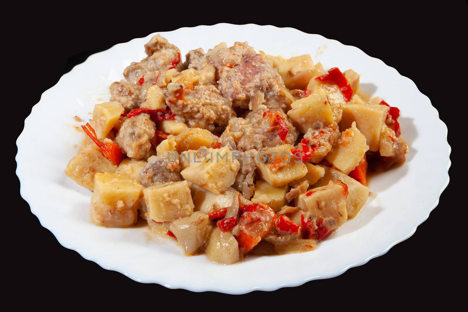 Plate with roasted meat and potatoes on a black studio background
