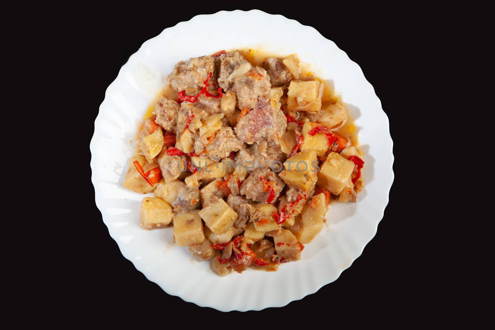 Plate with roasted meat and potatoes on a black studio background