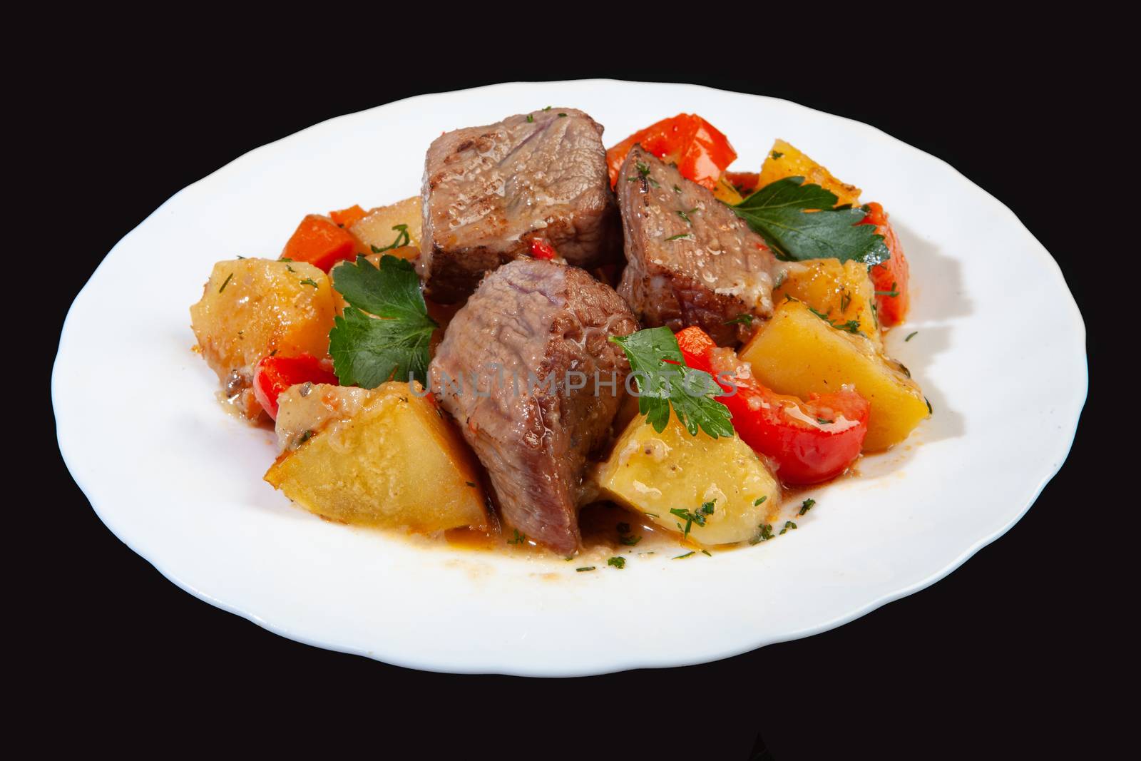 Plate with roasted meat and potatoes on a black studio background