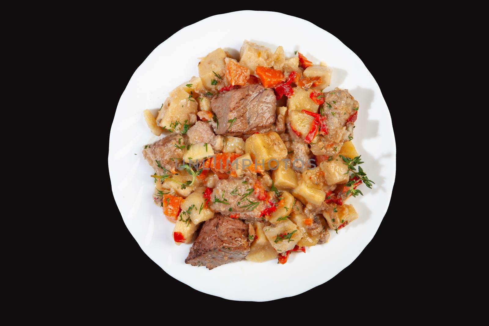 Plate with roasted meat and potatoes on a black studio background