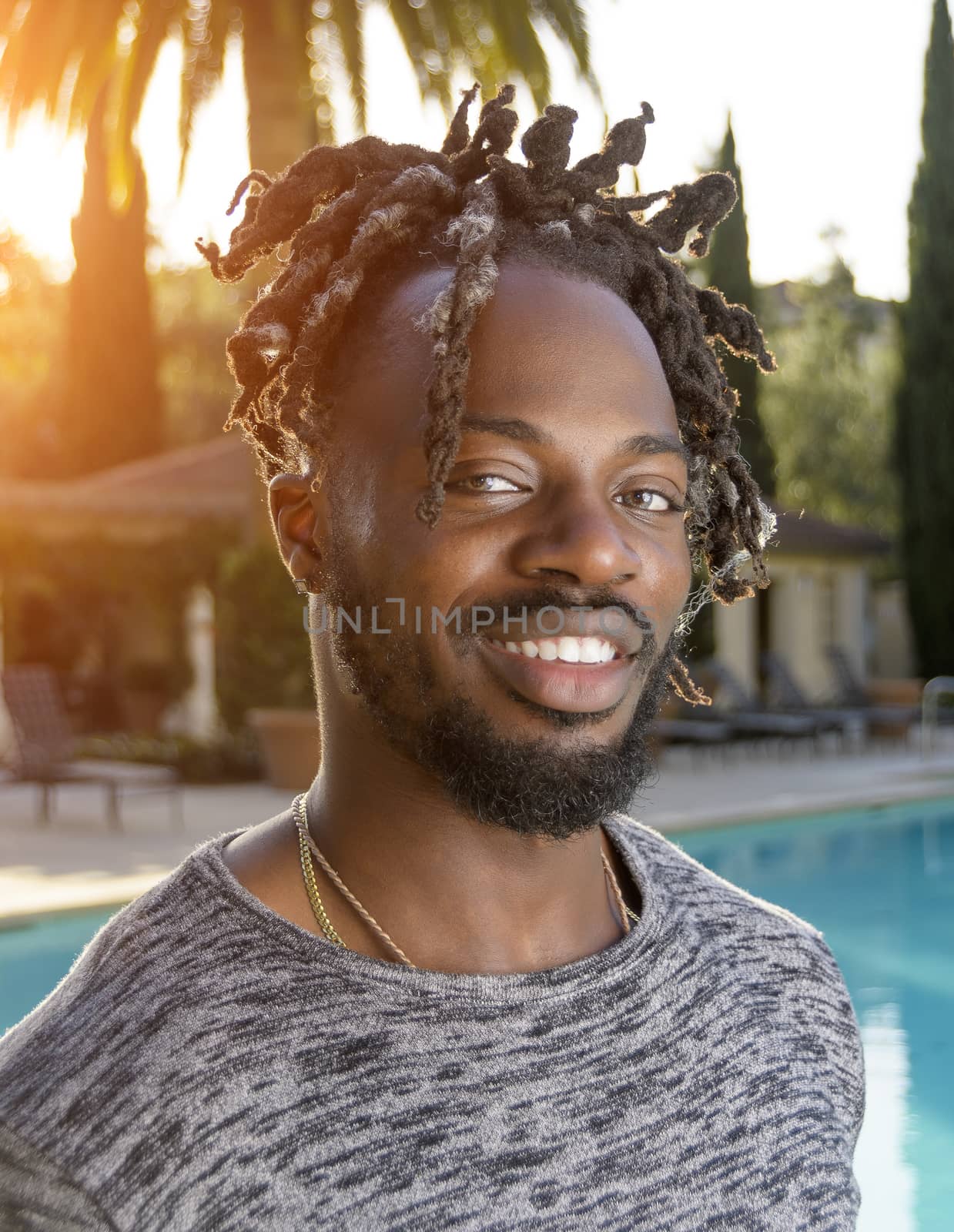 Portrait of a handsome young African American man smiling backlit by the afternoon sun.