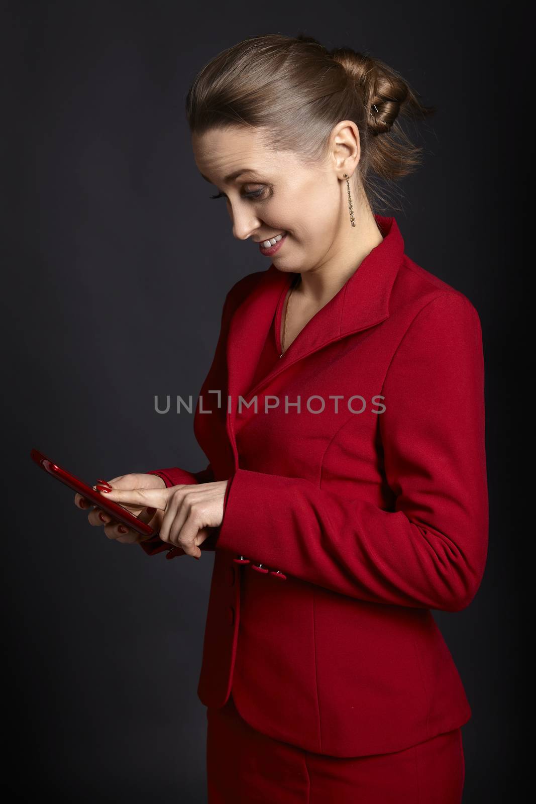 Studio shot of elegant young businesswoman using cell phone on black background.
