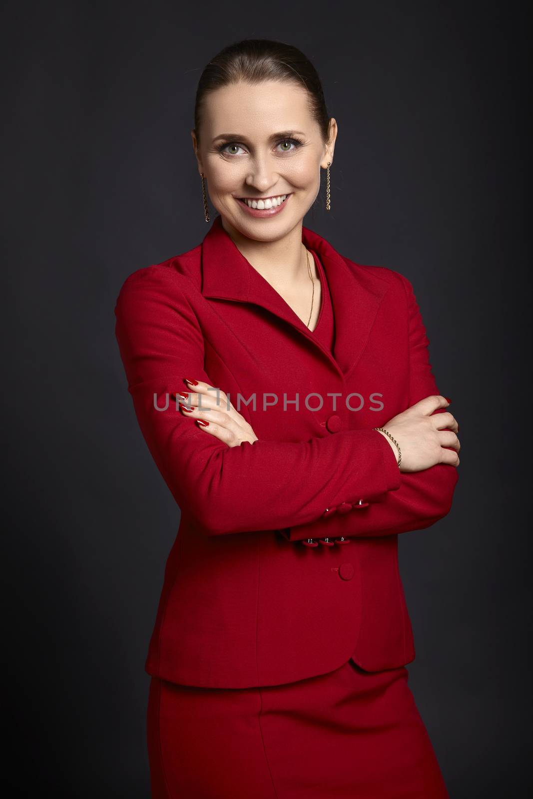 Portrait of elegant young woman with white smile and crossed arms looking at the camera, Studio shot on black background.