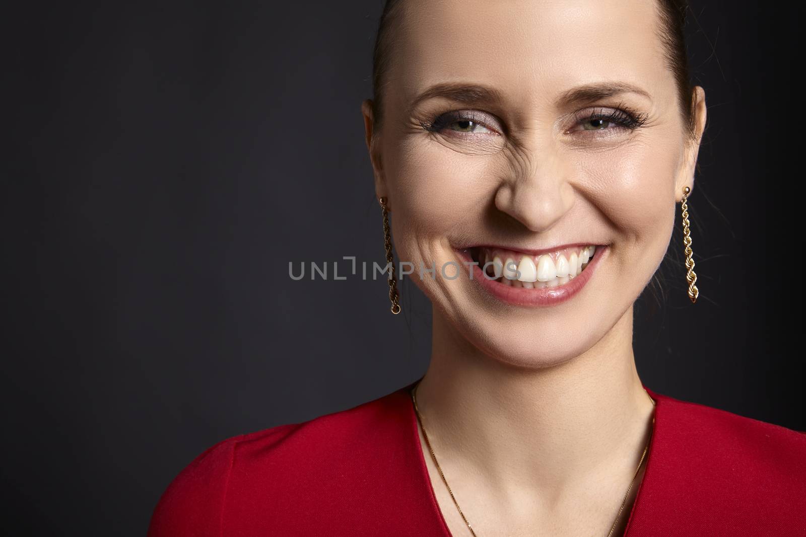 Close-up of young attractive woman with white smile on black background.