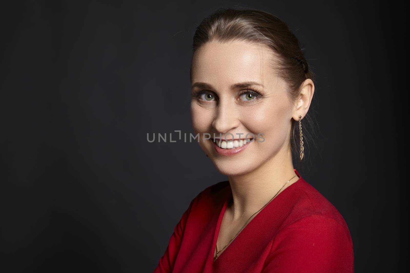 Studio portrait of young satisfied woman with white smile and green eyes on black background.