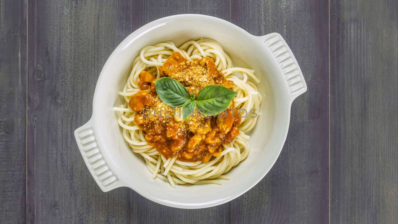 Plate of delicious spaghetti bolognese with savory minced beef and tomato sauce garnished with  basil, overhead view