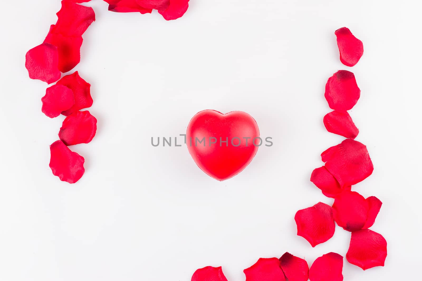 Heart and frame of artificial rose petals on white background