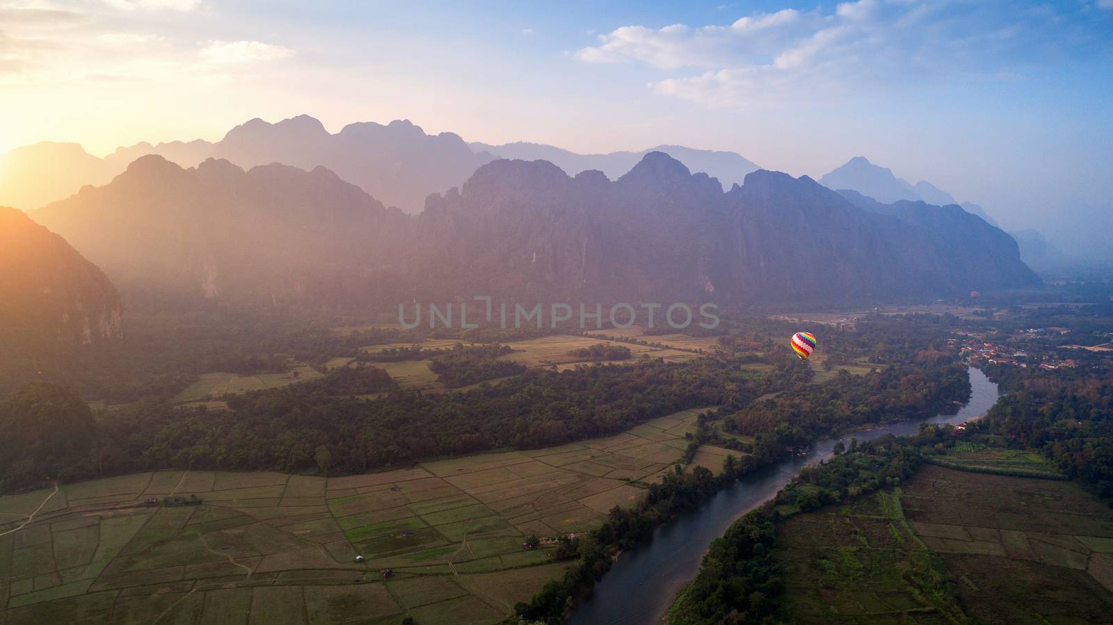 Aerial view of Vang vieng with mountains and balloon at sunset.
