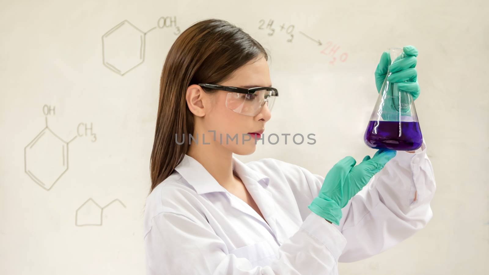 Portrait of Asian scientific researcher holding at a liquid solution in a lab
