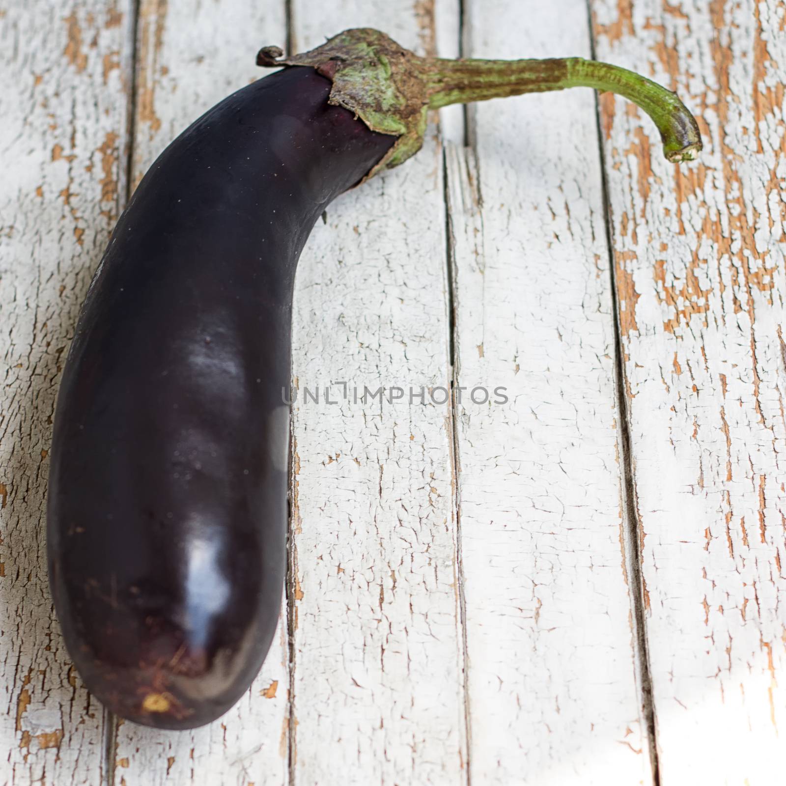 Raw eggplant with water drops on wooden table