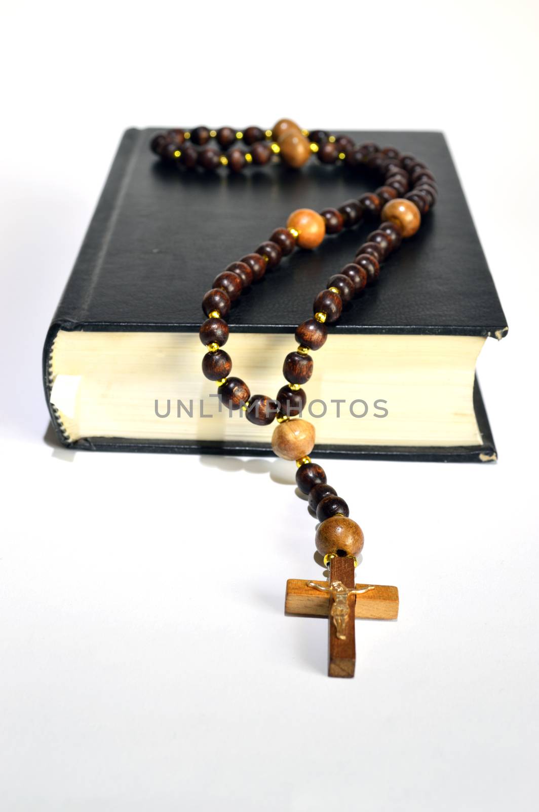 black book of the Bible with wooden rosary on white background