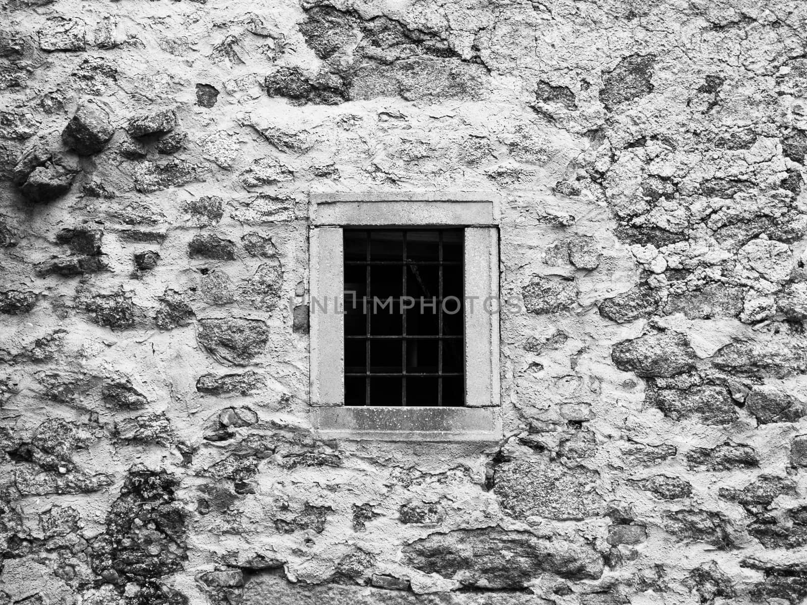 Old prison jail window with rusty metal bars. Vintage style image. Black and white image.