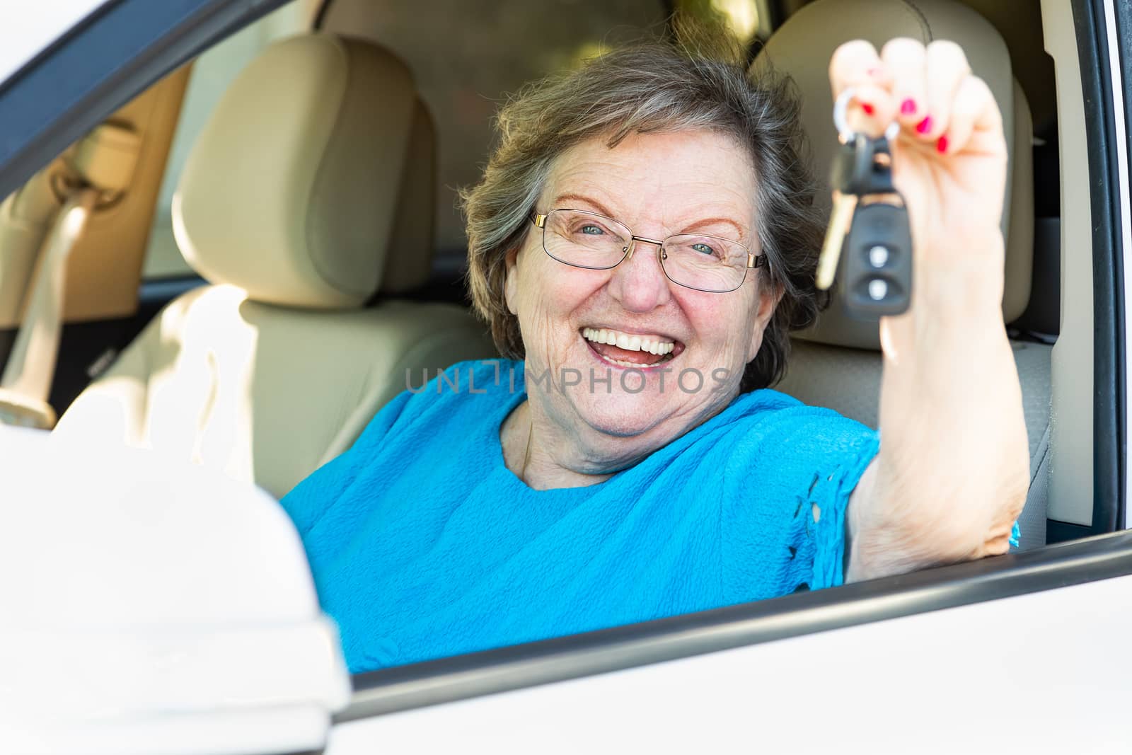 Happy Senior Woman Sitting In New Car Holding The Keys.