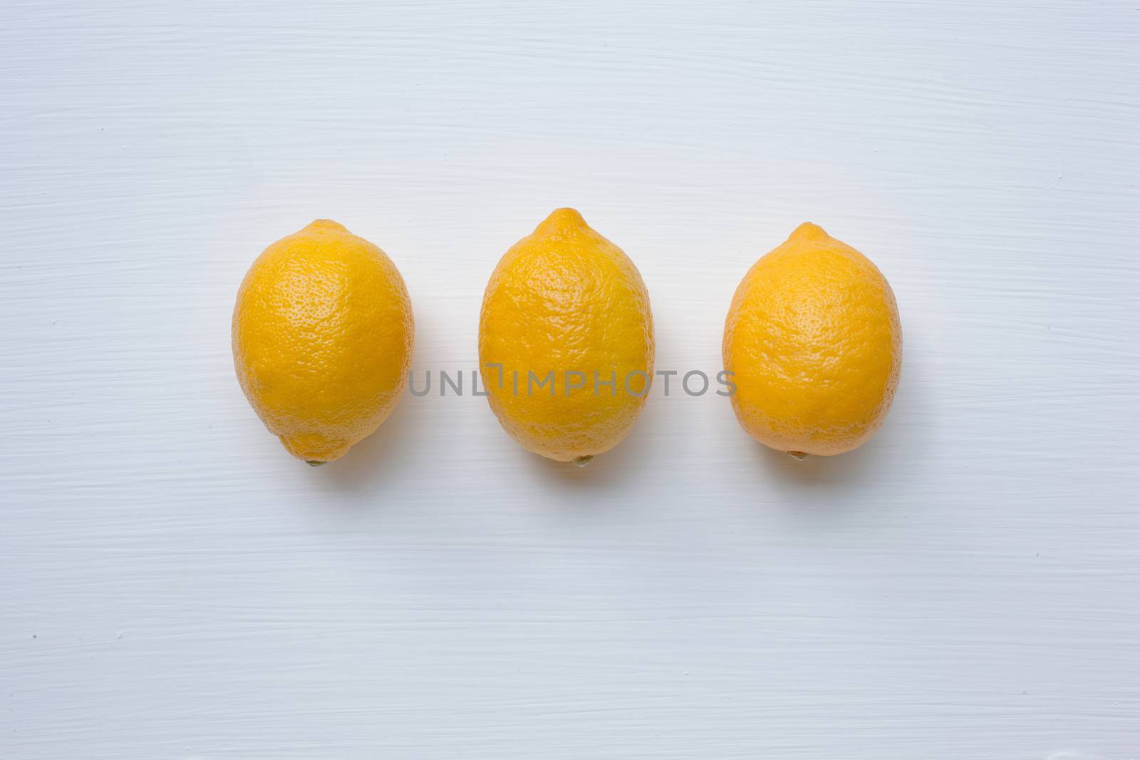 Three yellow lemons on a white background.