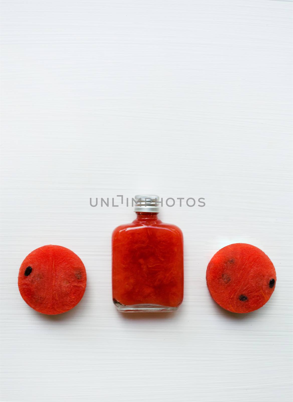 Bottle of fresh watermelon juice with  watermelon pieces  on white.