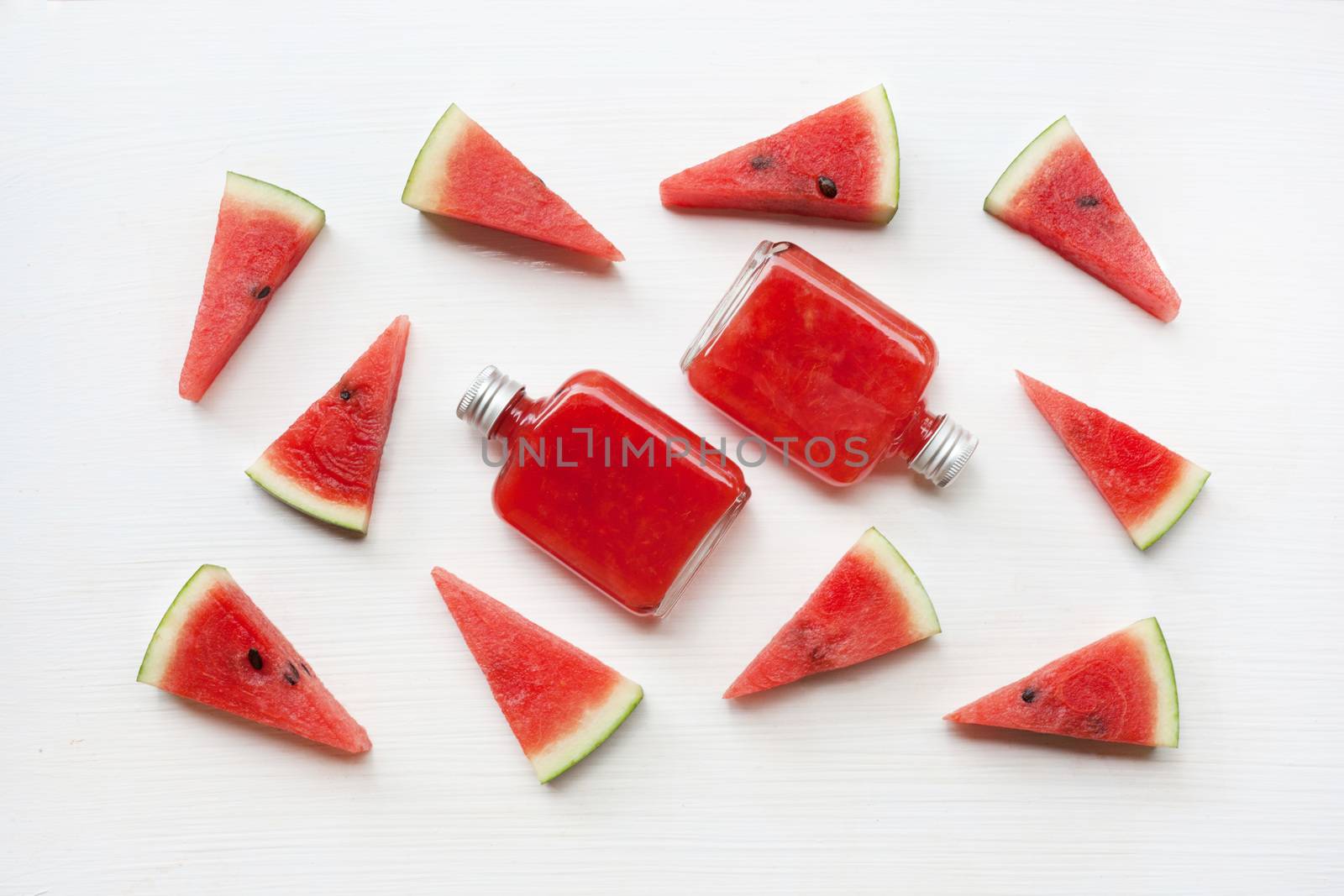 Bottle of fresh watermelon juice with  watermelon pieces  on white.