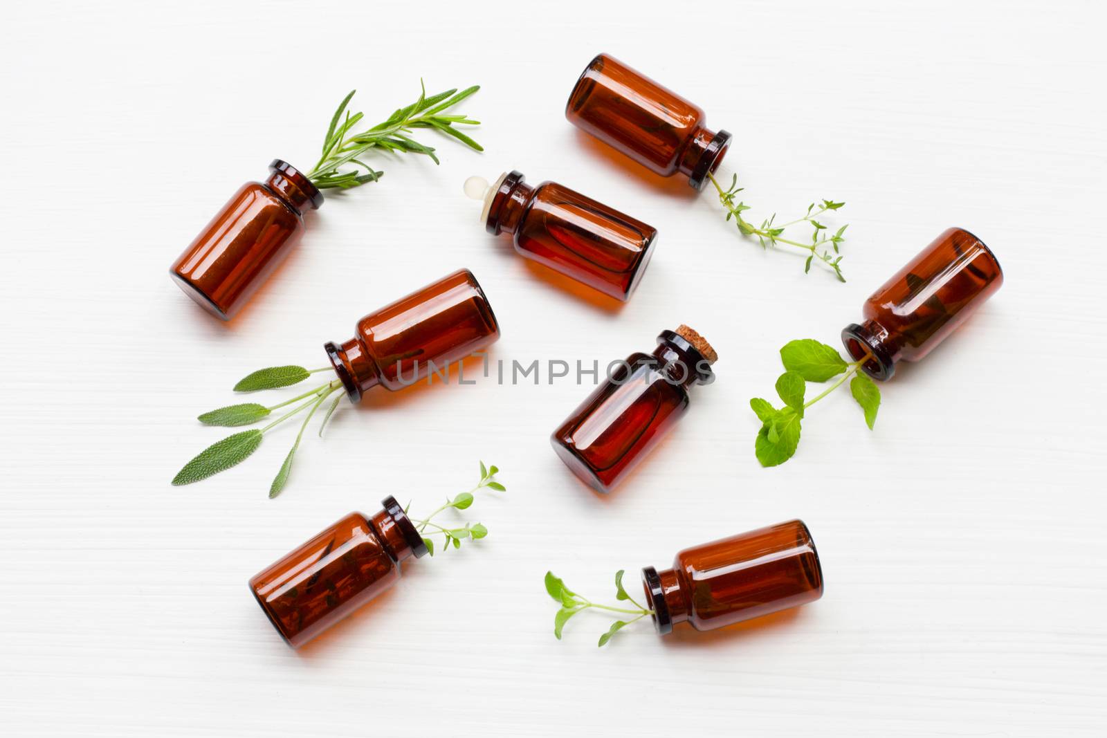 Top view, Bottle of essential oil with herbs  sage, rosemary, oregano, mint, thyme and lemon thyme  on white background.