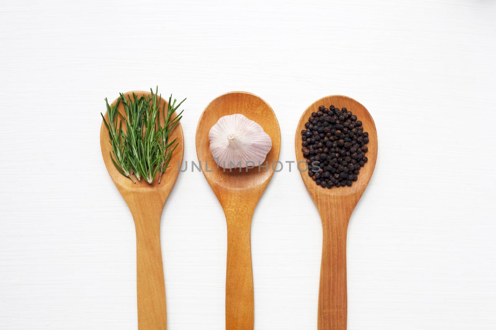 Garlic with rosemary and black peppercorn isolated on white wooden background
