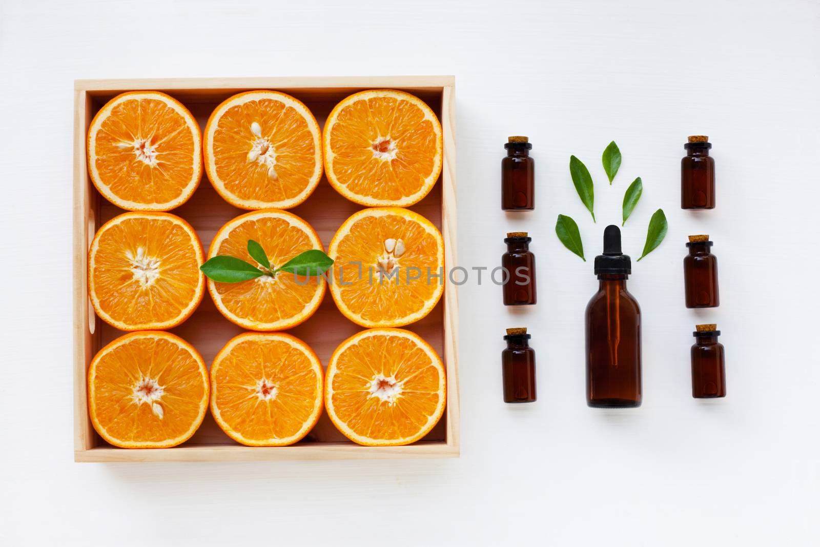 Bottle of essential oil from oranges citrus fruit with fresh orange and leaves on white background.