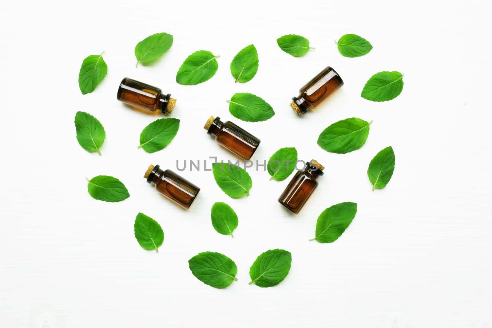 Essentail oil with fresh mint leaves on white background.