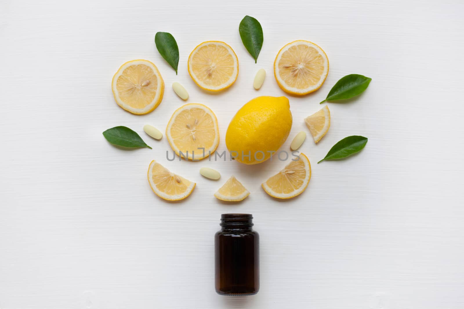 Brown Bottle with lemon, leaves and vitamin C. on white background.