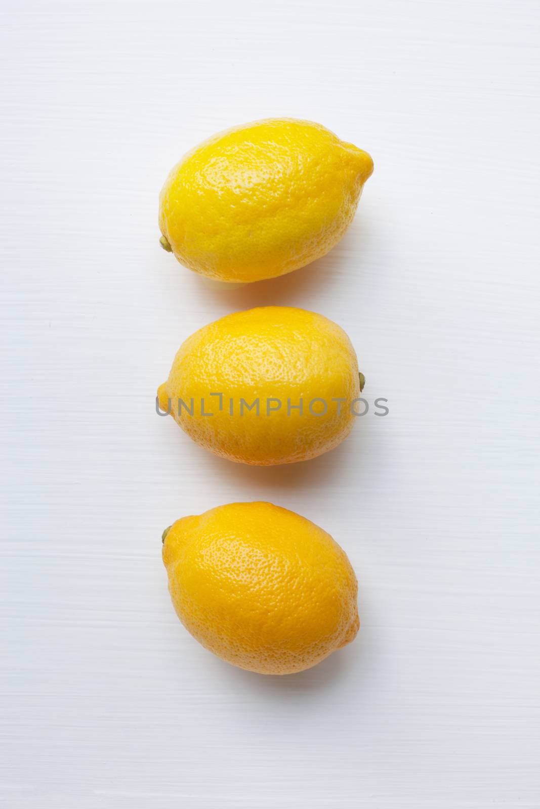 Three yellow lemons on a white background.