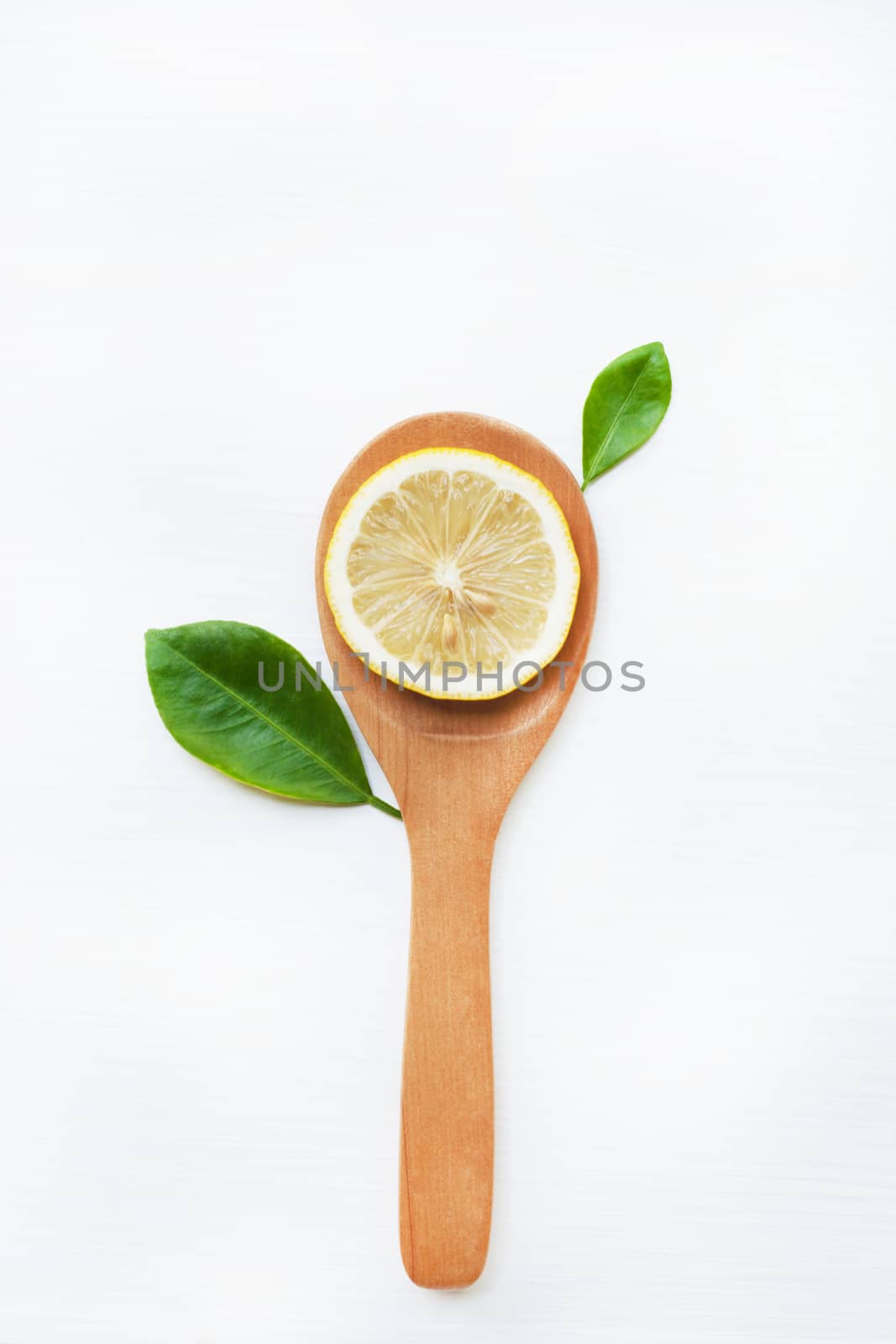 Lemon slices on wooden spoon with leaf isolated on white background, top view