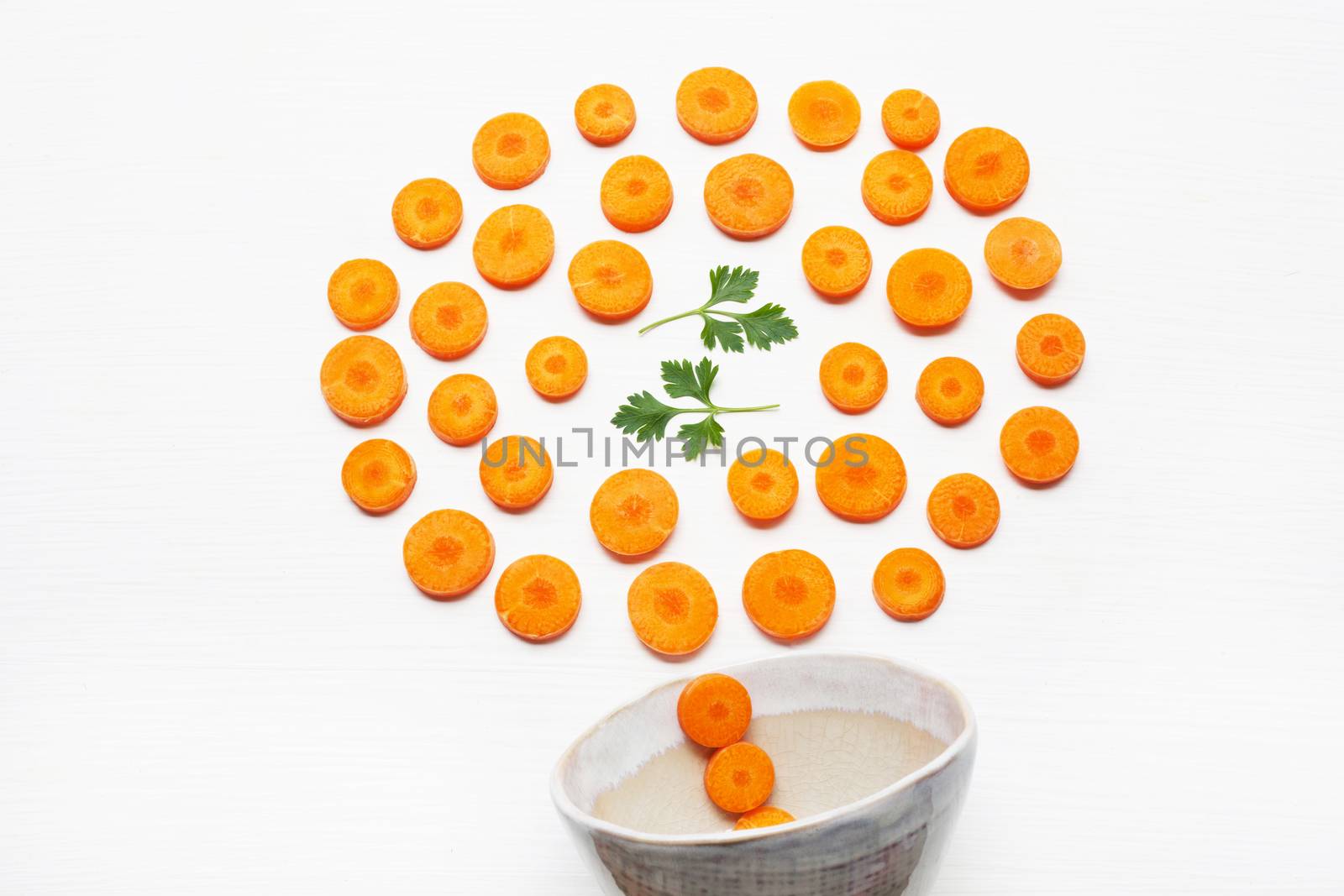 Chopped carrot slices  and parsley leaves with bowl  isolated on white background.