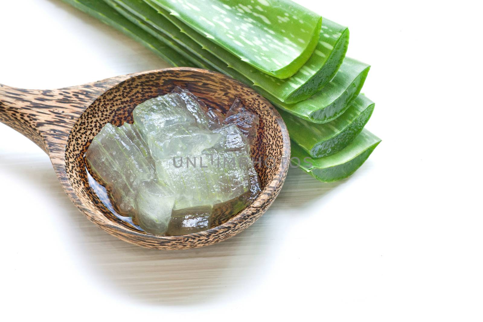 Aloe vera fresh leaves with aloe vera gel on wooden spoon, isolated white background.
