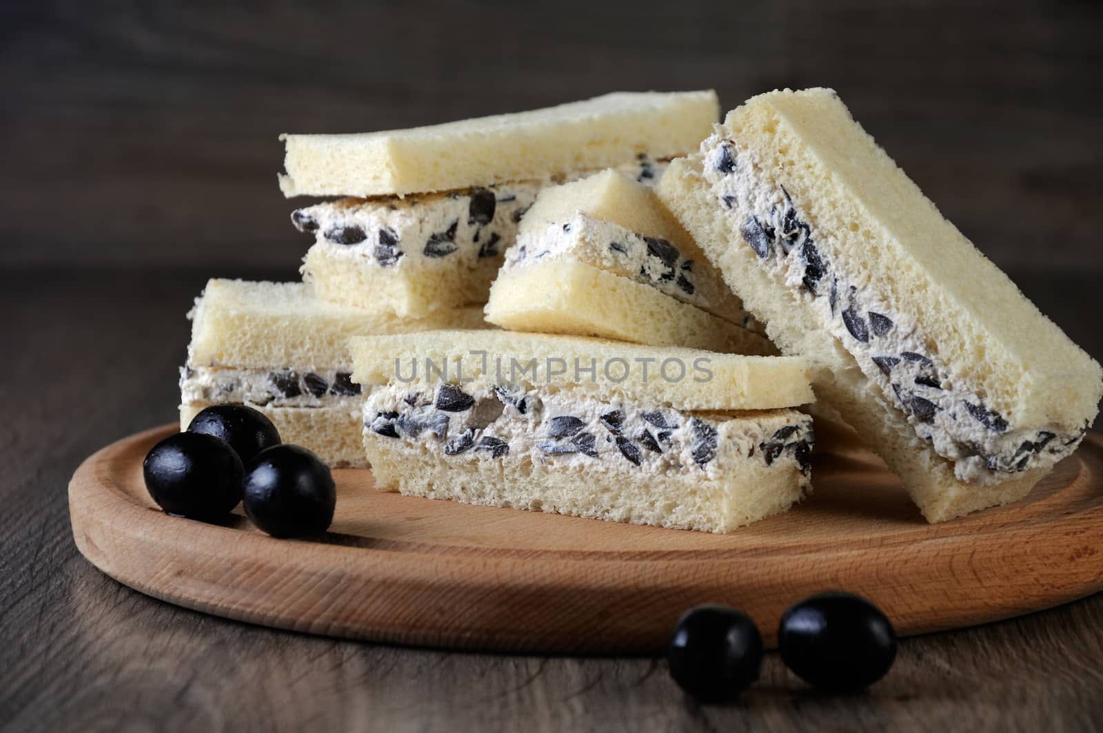 Slices of sandwich with ricotta and black olives