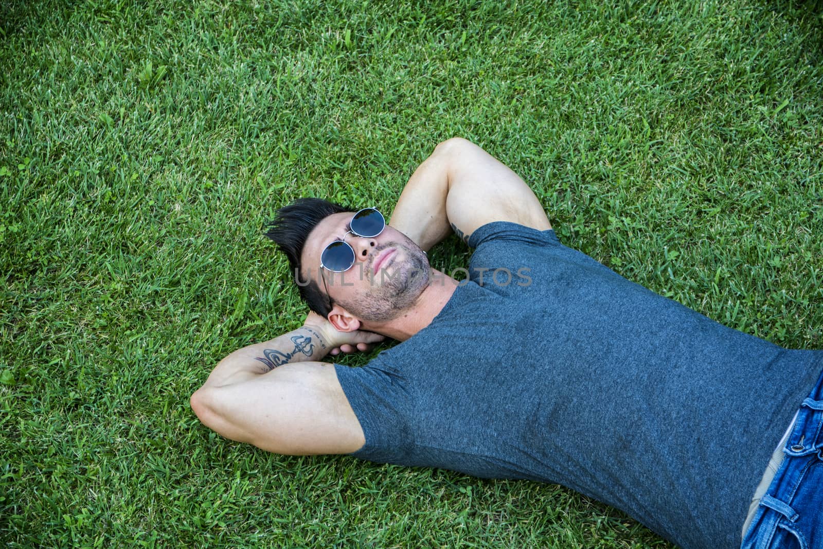 Good looking, fit male model relaxing lying on the grass by artofphoto