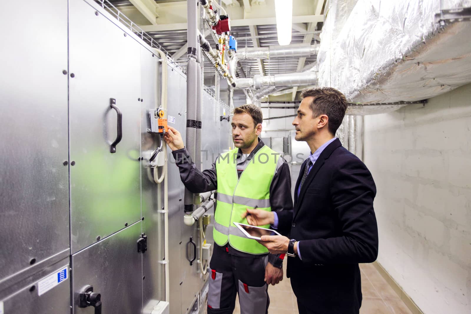 Worker and manager in electrical switchgear room of CNC plant