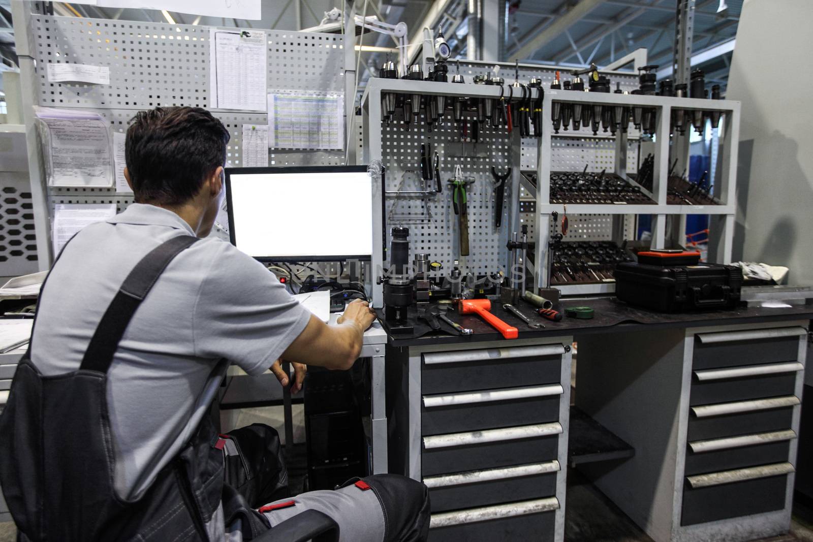 Worker at workplace with computer and tools at CNC factory