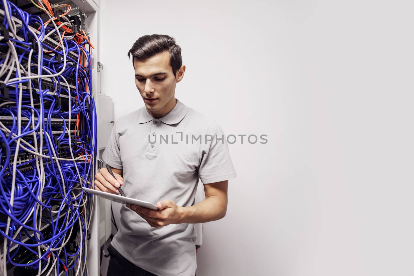 Young engeneer man in network server room with digital tablet