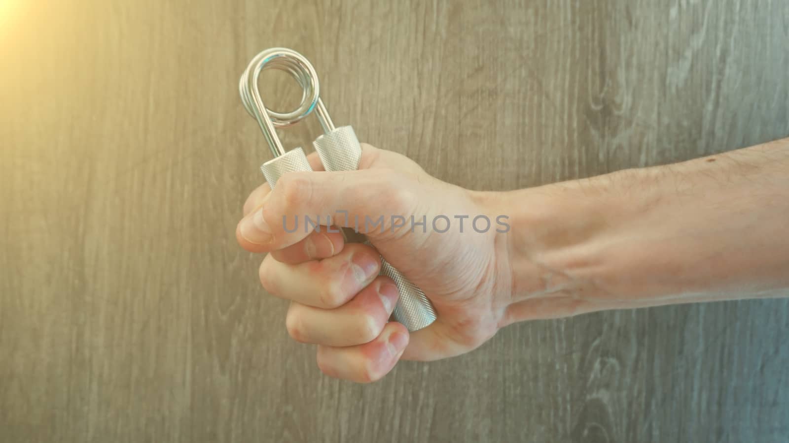 hand expander in the hand of a young athlete. sun effect.