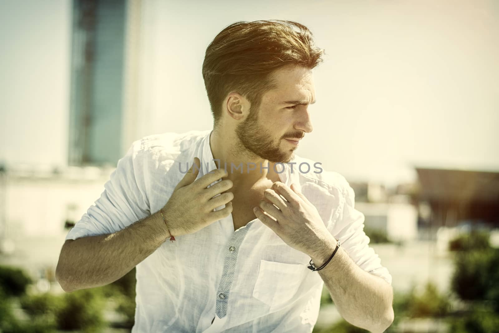 One attractive young man in urban setting in modern city, leaning against balusters