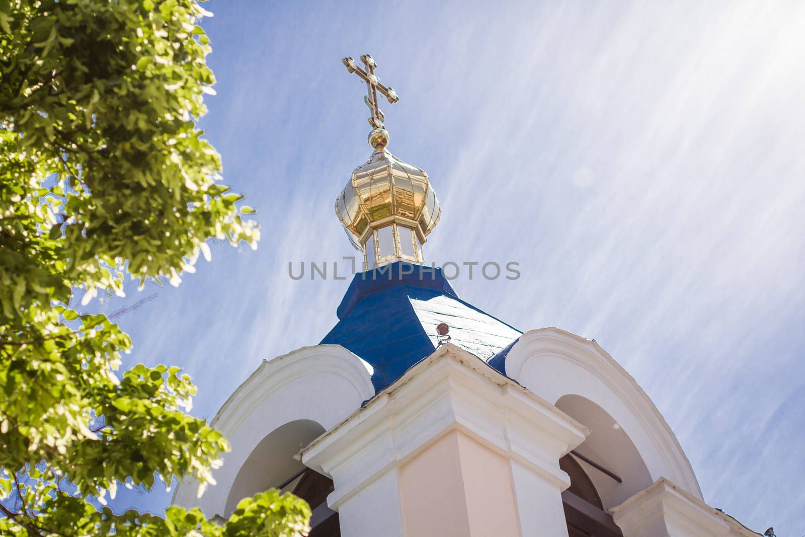 Part of orthodox church roof with cross over blue sky