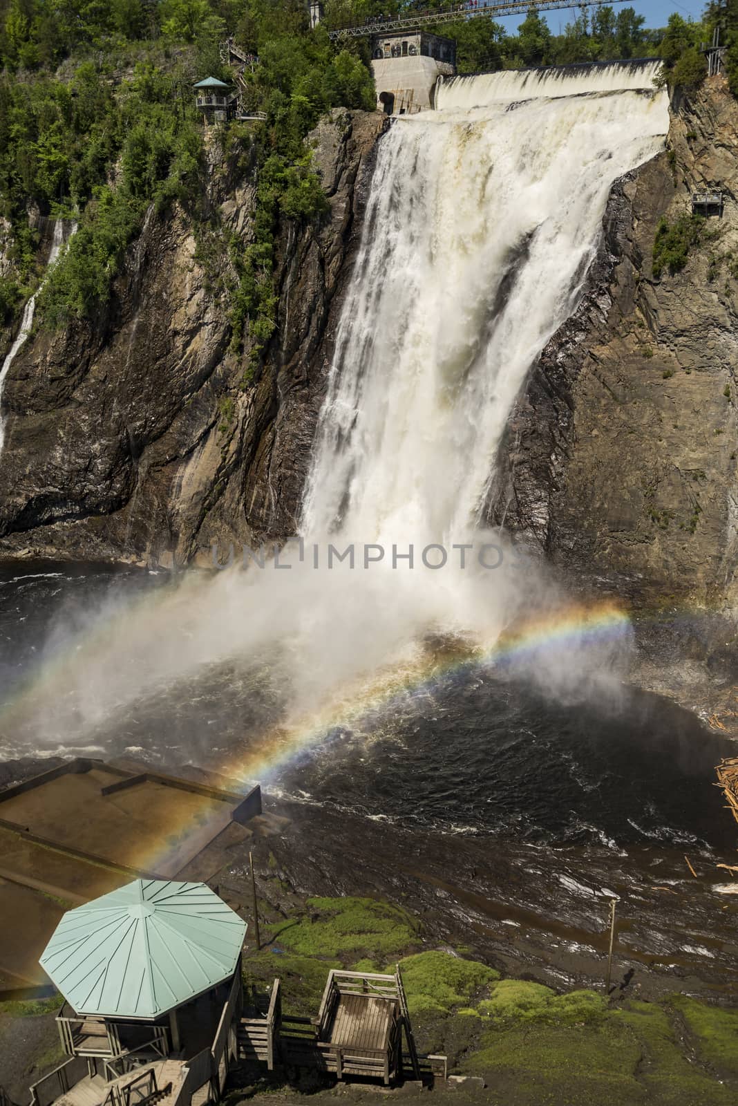 The magnificent rainbow plays in falls splashes. The blue lake and powerful waterfall Montmorency in Montmorency Falls Park, in Quebec. The concept of active and cultural tourism
