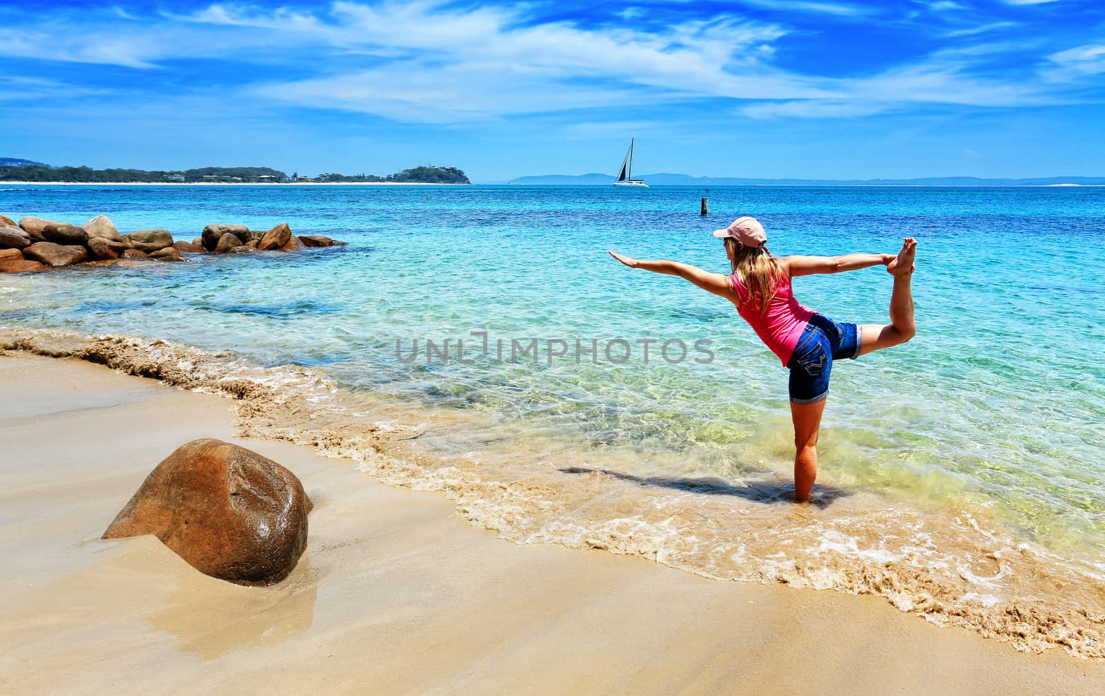Balancing on moving sand.  A woman practices yoga on the beach with the shifting sands and tidal flows adding an extra dimension and difficulty to the usual asanas.