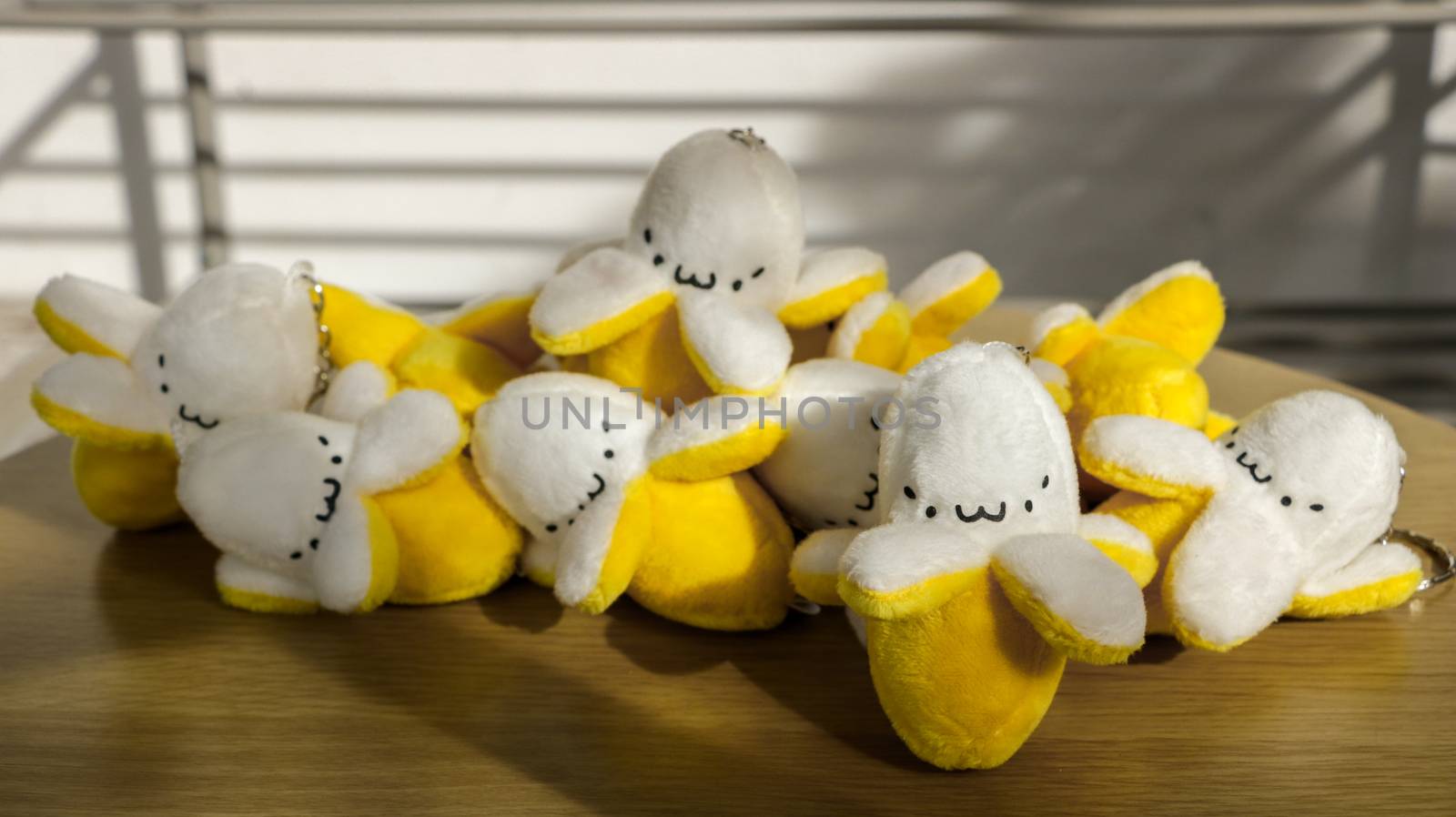 Miniature Stuffed Bananas/ Keychain/ Soft Toys with Cute Faces on Wooden Table in the Sun - Outdoors