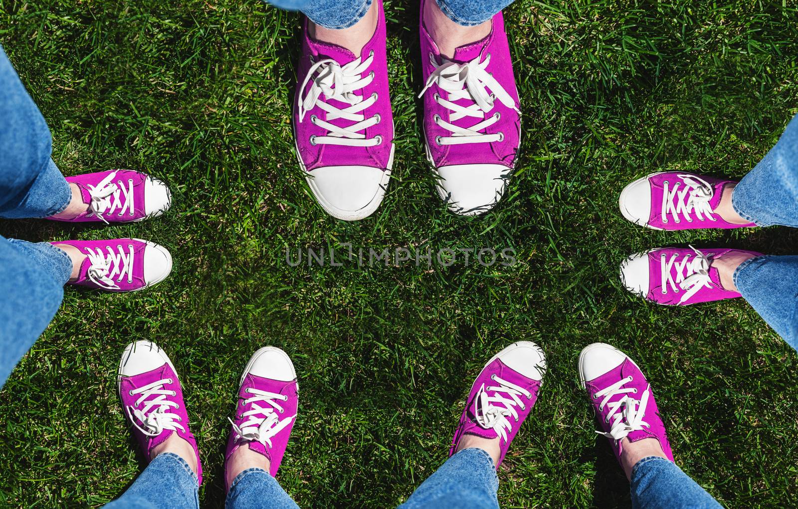 Collage of legs in old pink sneakers on green grass. View from above. The concept of youth, spring and freedom. Isolated on white background.