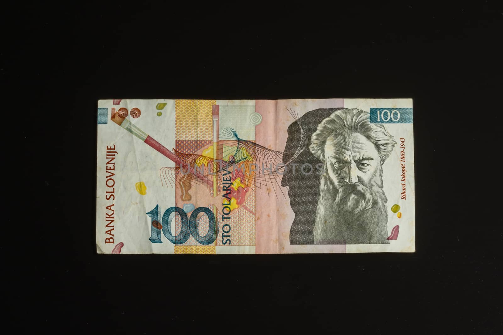 Obsolete 100 tolar bill of Slovenia, became obsolete with introduction of Euro currency, isolated on black background