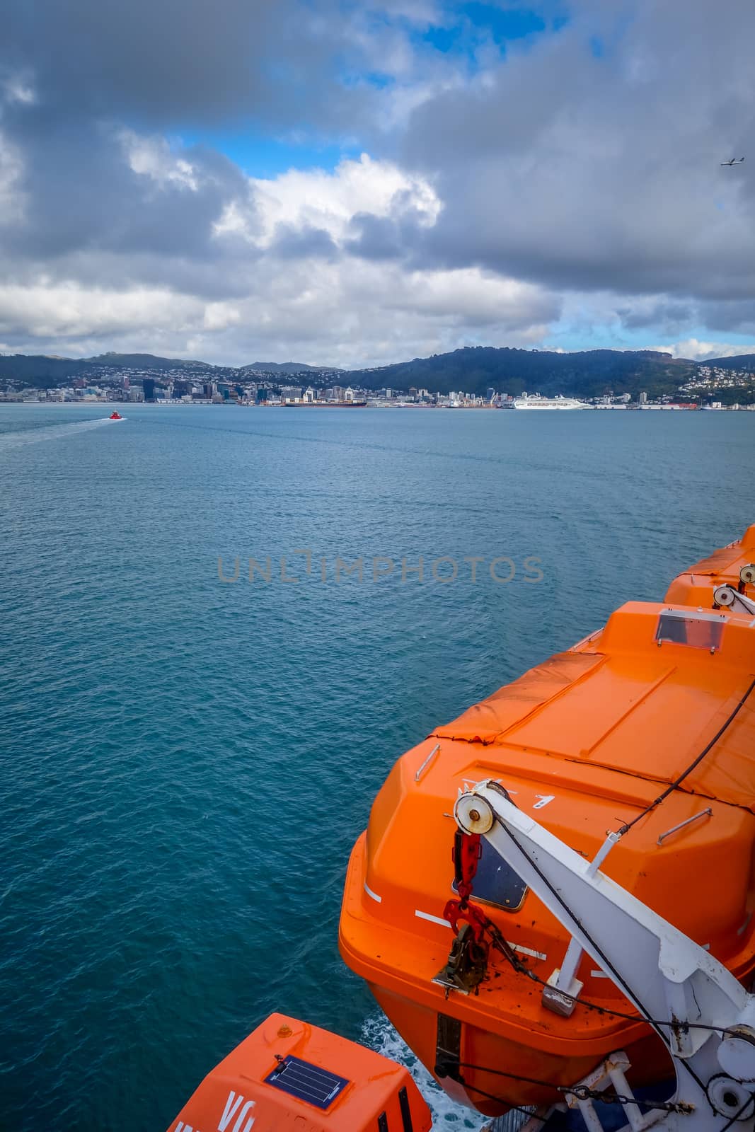 Wellington city and orange lifeboat view from a ferry. New Zealand north Island